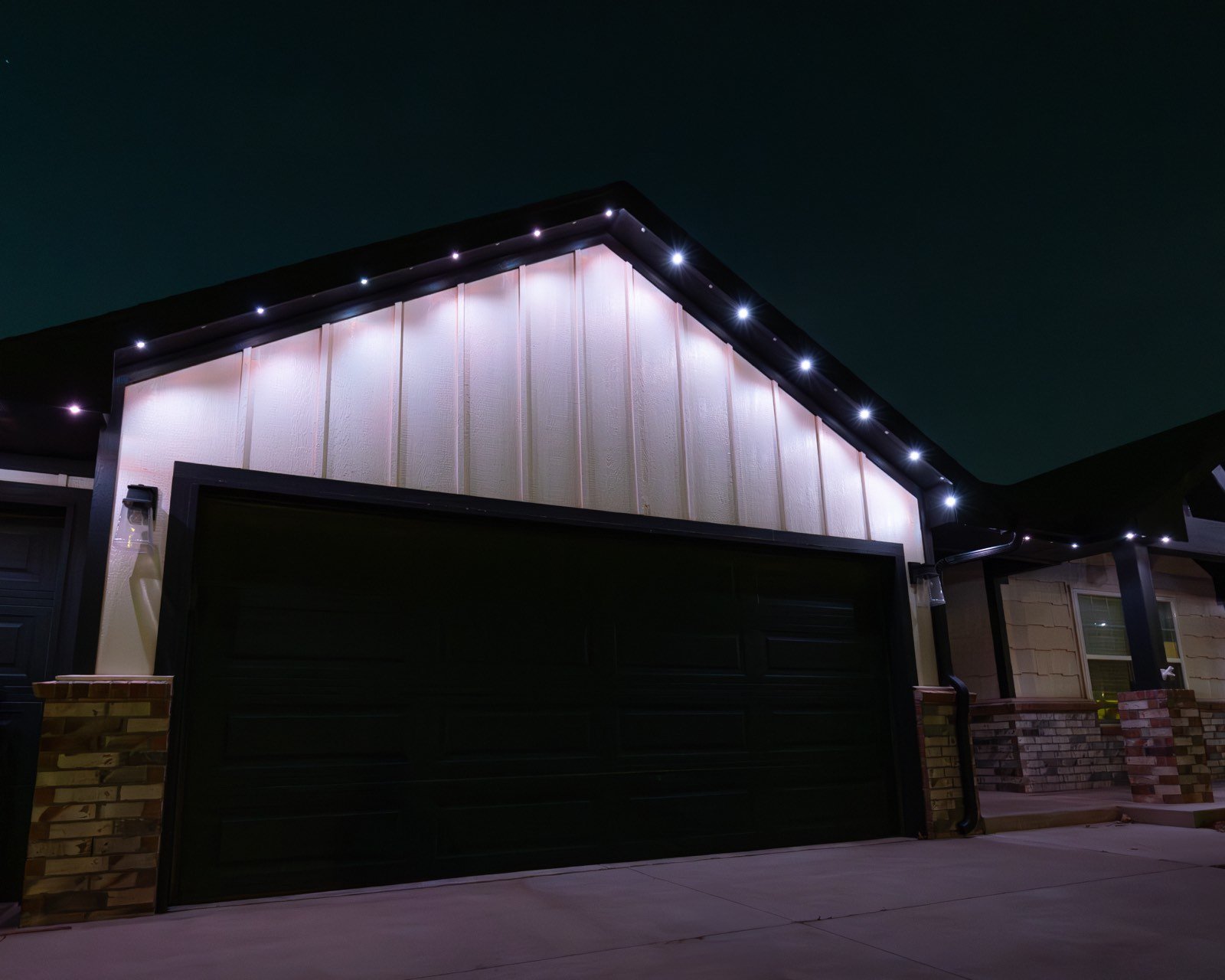 Warm white permanent accent lighting on a brick home at night