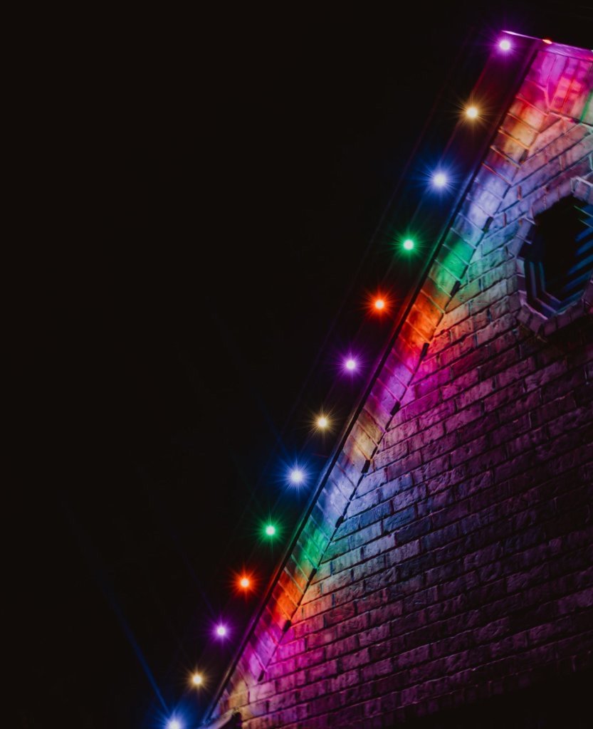 Close-up of multicolor LED lights along a brick roofline