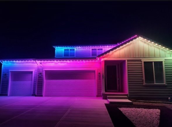 Home roofline and gable lit in blue, green, and purple permanent LED lighting